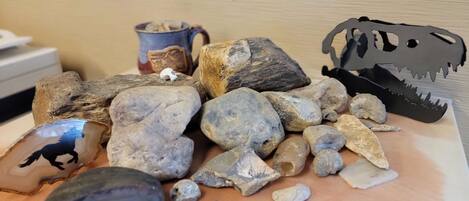 A collection of rocks and a paper cutout of a dinosaur on a wooden surface.
