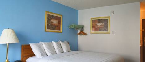 A bedroom with a bed, a nightstand, a lamp, and two framed pictures on the wall.