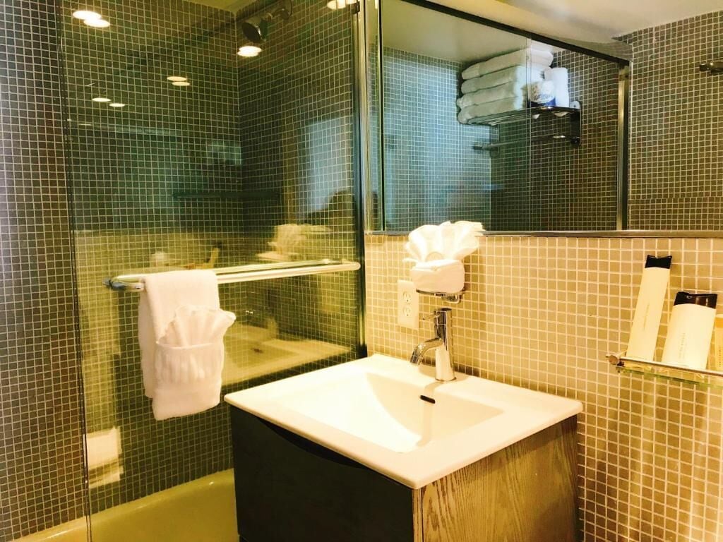A bathroom with a glass shower enclosure, a sink with a mirror, and a towel rack.