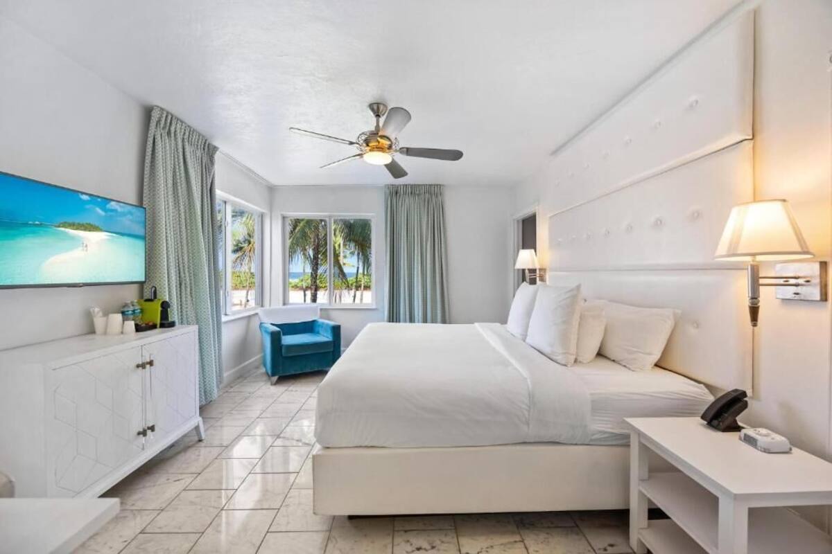 A hotel room with a bed, a desk, a chair, a TV, and a ceiling fan.