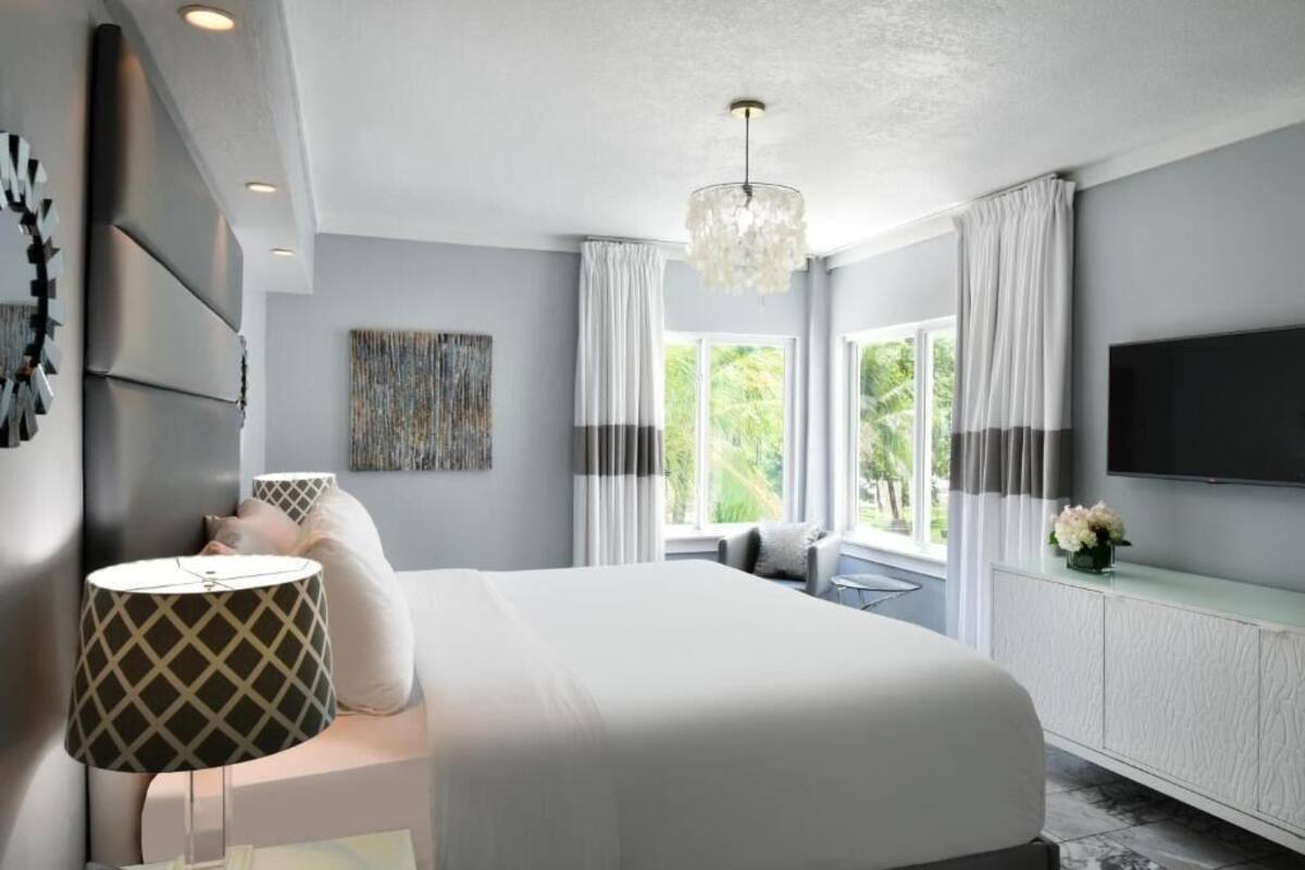 A modern bedroom with a large bed, a TV, and a chandelier.