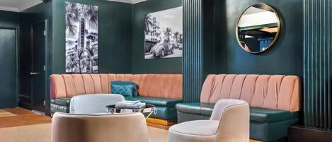 A modern living room with a green sofa, a white armchair, and a coffee table. There are two large black-and-white photographs on the wall.