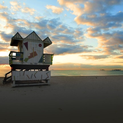 A lifeguard tower on a beach with a sunset in the background.