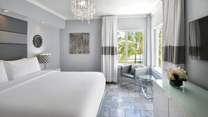 Een moderne hotelkamer met een groot bed, een zithoek met een fauteuil, een tafeltje, een decoratief muurdecor en een raam met gordijnen.