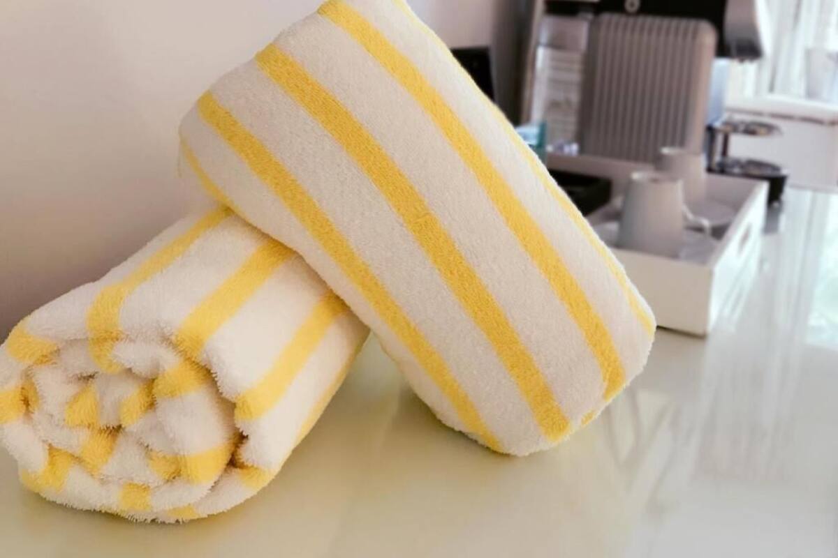 Two rolled towels with yellow stripes on a white surface.