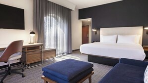 Una habitación de hotel con cama, escritorio, silla y sofá.