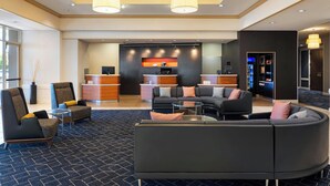 Un moderno vestíbulo de hotel con mostrador de recepción, zona de estar y bar.