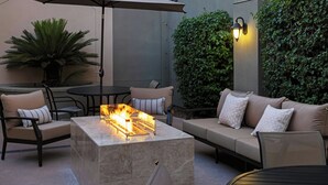 Un espacio de patio al aire libre con una chimenea, asientos y una pared cubierta de vegetación.