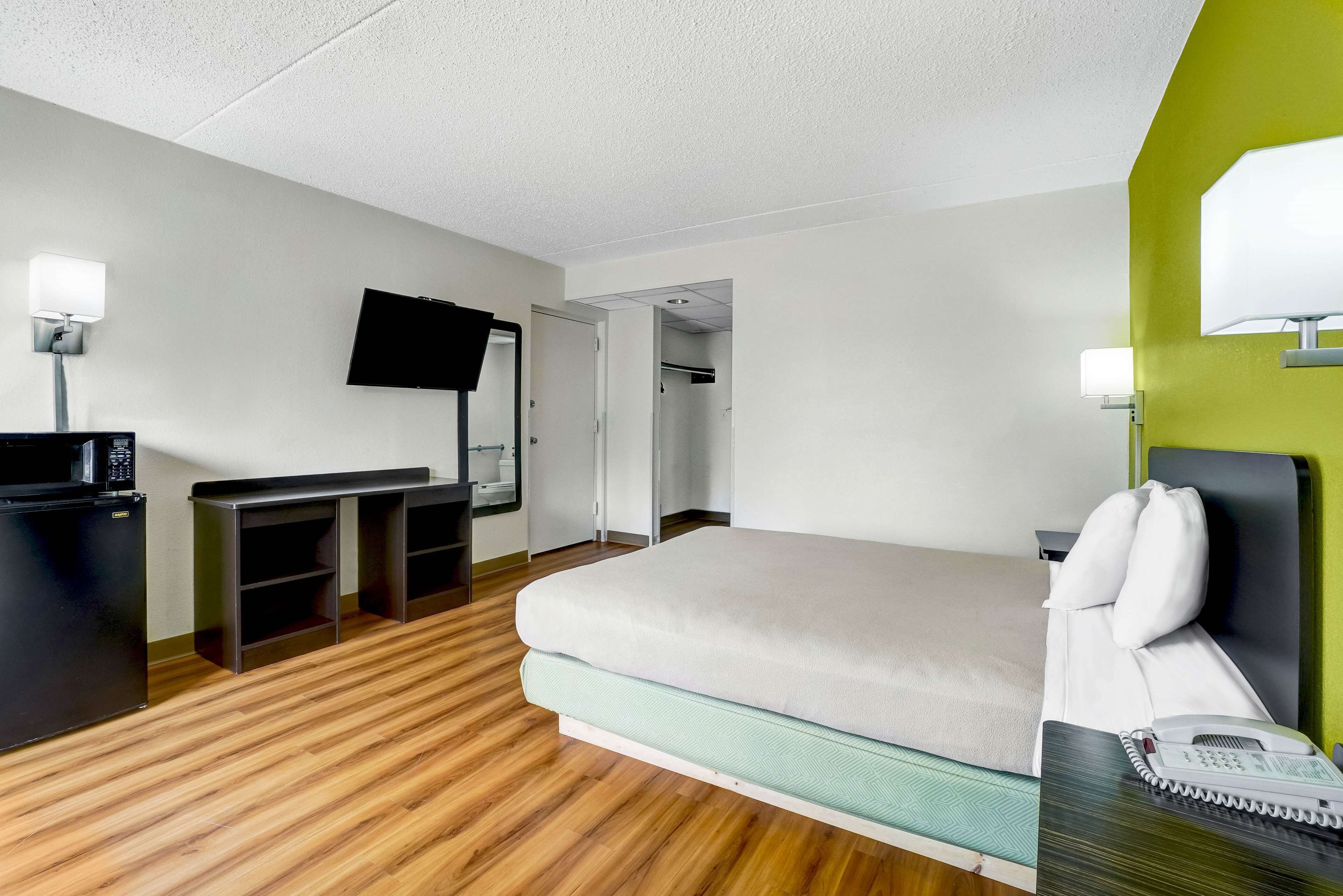 A hotel room with a bed, desk, and TV.