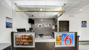 Uma receção de hotel com um relógio, fotografias emolduradas e um sinal a indicar a sala número 6.