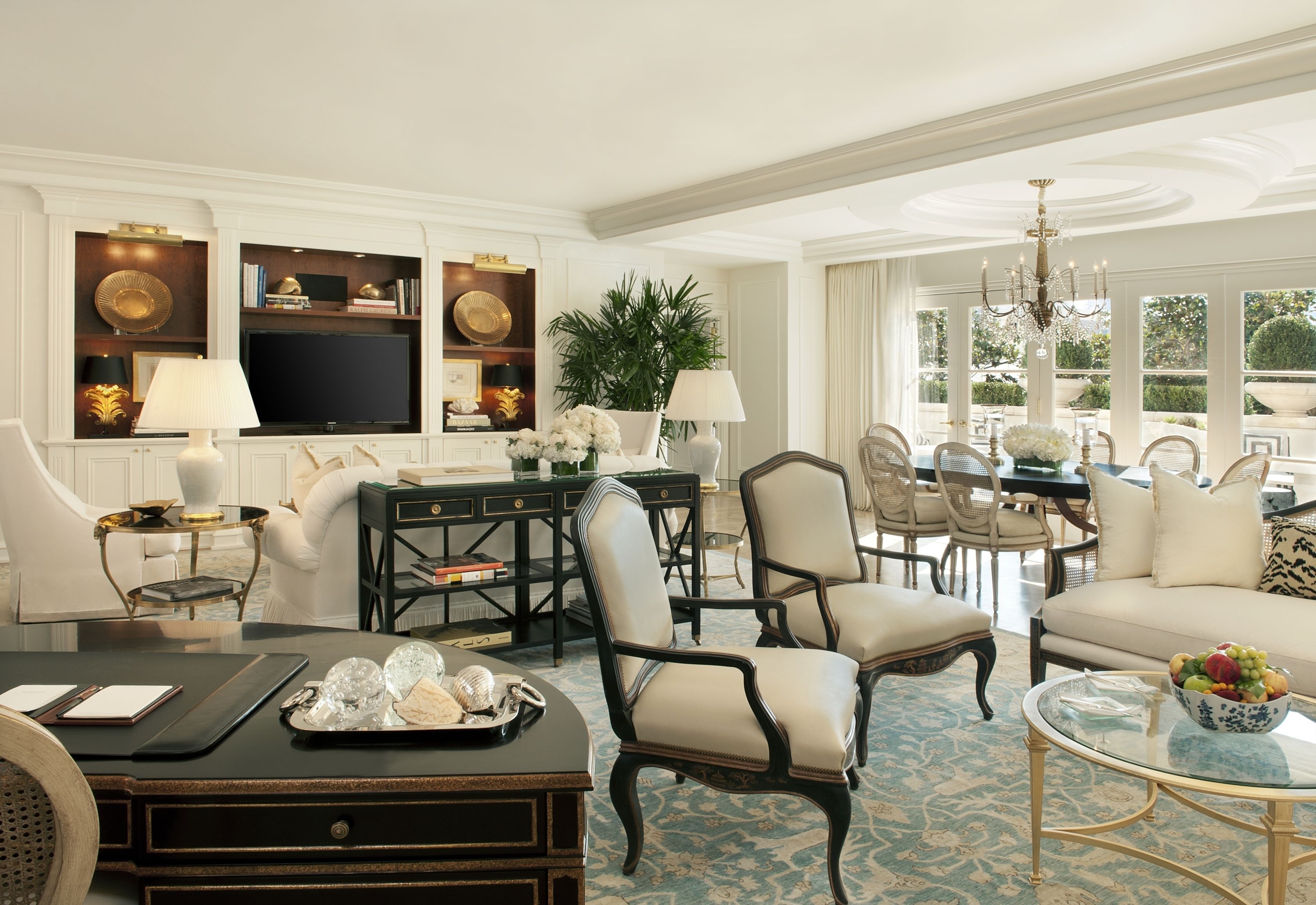 A spacious living room with a large television, comfortable seating, a dining area, and a view of the outdoors.
