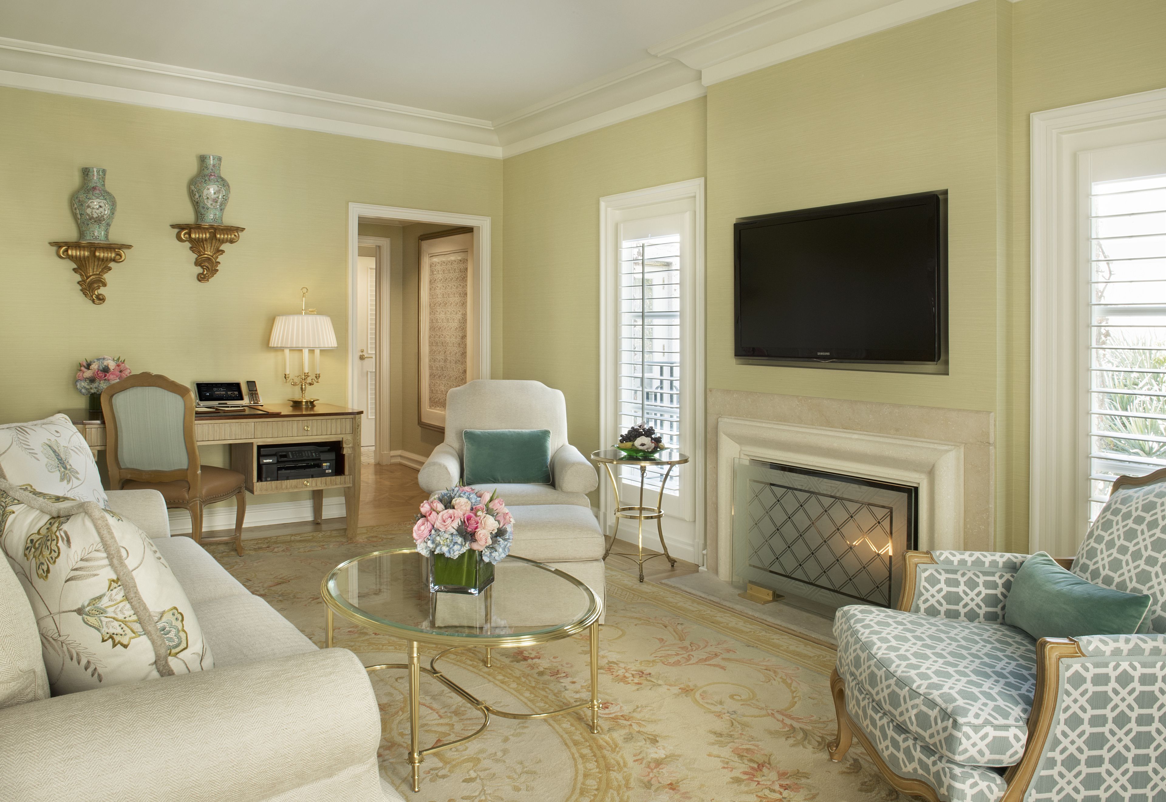 A living room with a fireplace, a television mounted above it, and a comfortable seating area with a sofa and armchairs.