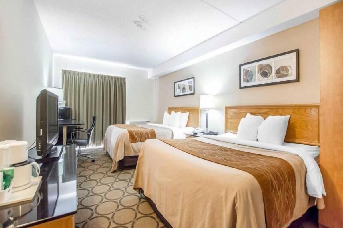 A hotel room with two beds, a desk with a computer, a TV, and a coffee station.