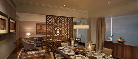 A dining area with a long table set for six, surrounded by chairs, with a decorative partition and a city view through the window.