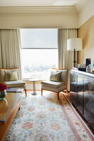 A hotel room with two armchairs, a small table, a lamp, and a cabinet.