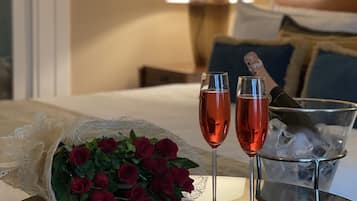 Ein Tisch mit einem Rosenstrauß, zwei Sektgläsern mit Eiswürfeln und Schokoladen-Erdbeeren.