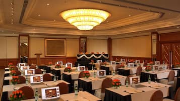 Sala de conferência com várias mesas, laptops e centros de mesa florais.