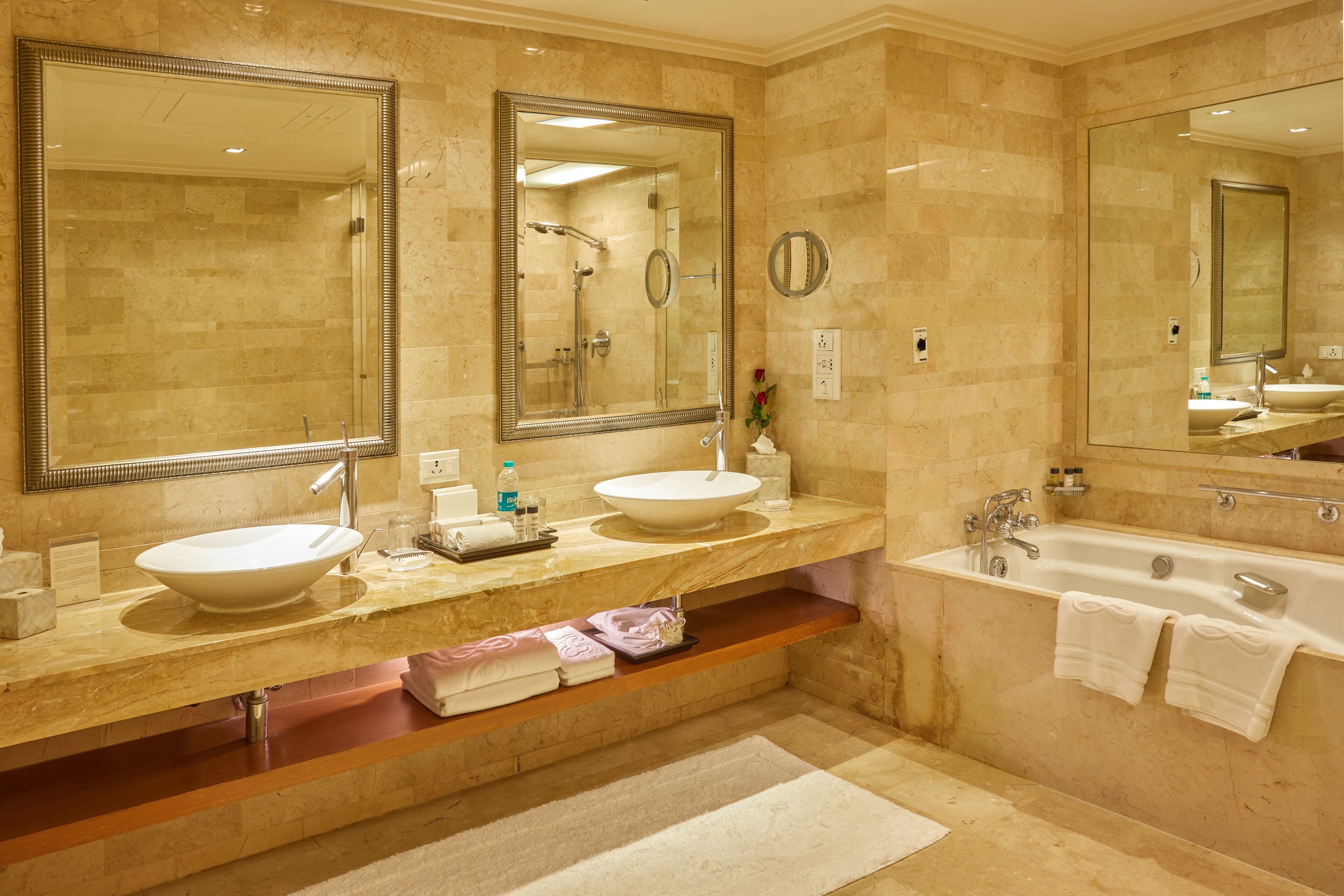 Un baño con dos lavamanos, una bañera y espejos grandes.