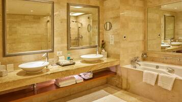 Un baño con dos lavamanos, una bañera y espejos grandes.