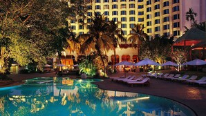 Un hotel con piscina, palmeras y sillones de descanso.