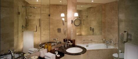 A modern bathroom with two sinks, a large mirror, a bathtub, and a glass shower enclosure.