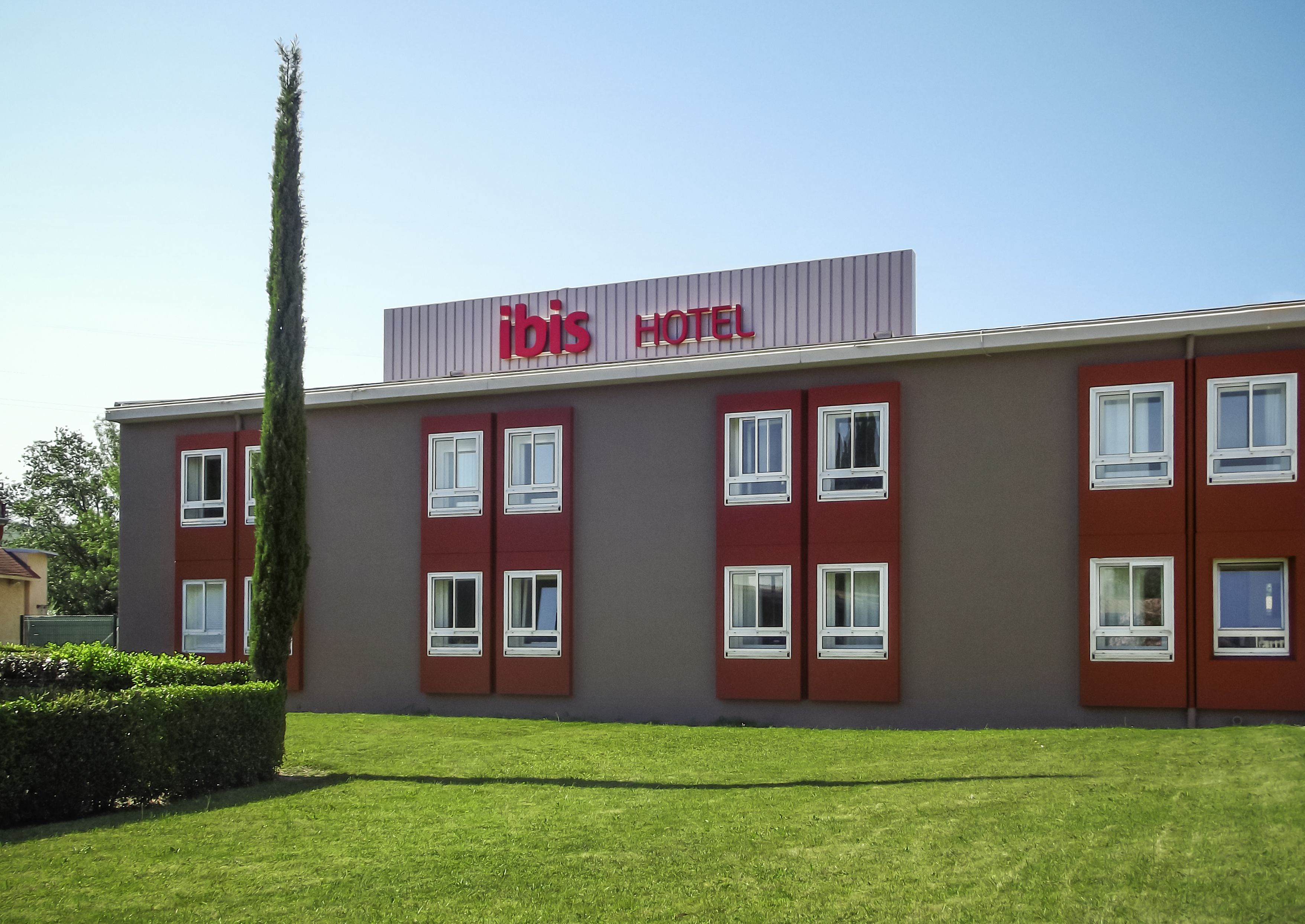 A building with a sign reading "Ibis Hotel" and multiple windows.