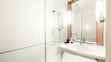 Un baño moderno con cabina de ducha de vidrio, un lavabo blanco y un espejo con marco de madera.