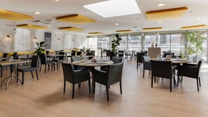 A spacious restaurant with high ceilings, modern lighting, and large windows. - ibis Montelimar Nord (Saulce-sur-Rhone)