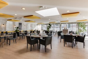 Un restaurante espacioso con techos altos, iluminación moderna y amplias ventanas.