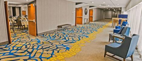 A hotel lobby with a patterned carpet, seating area, and a reception desk.