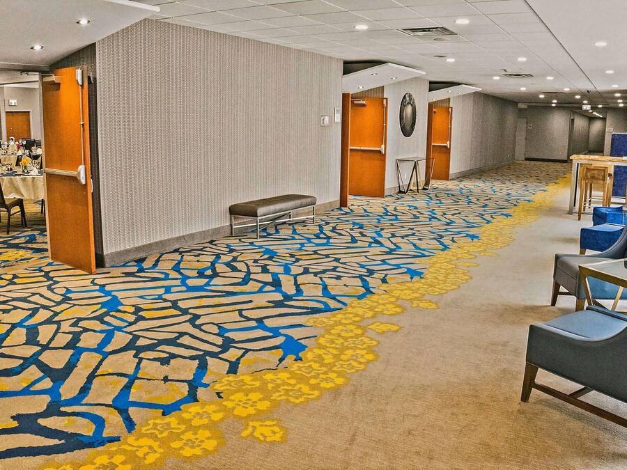 A hotel lobby with a patterned carpet, seating area, and a reception desk.