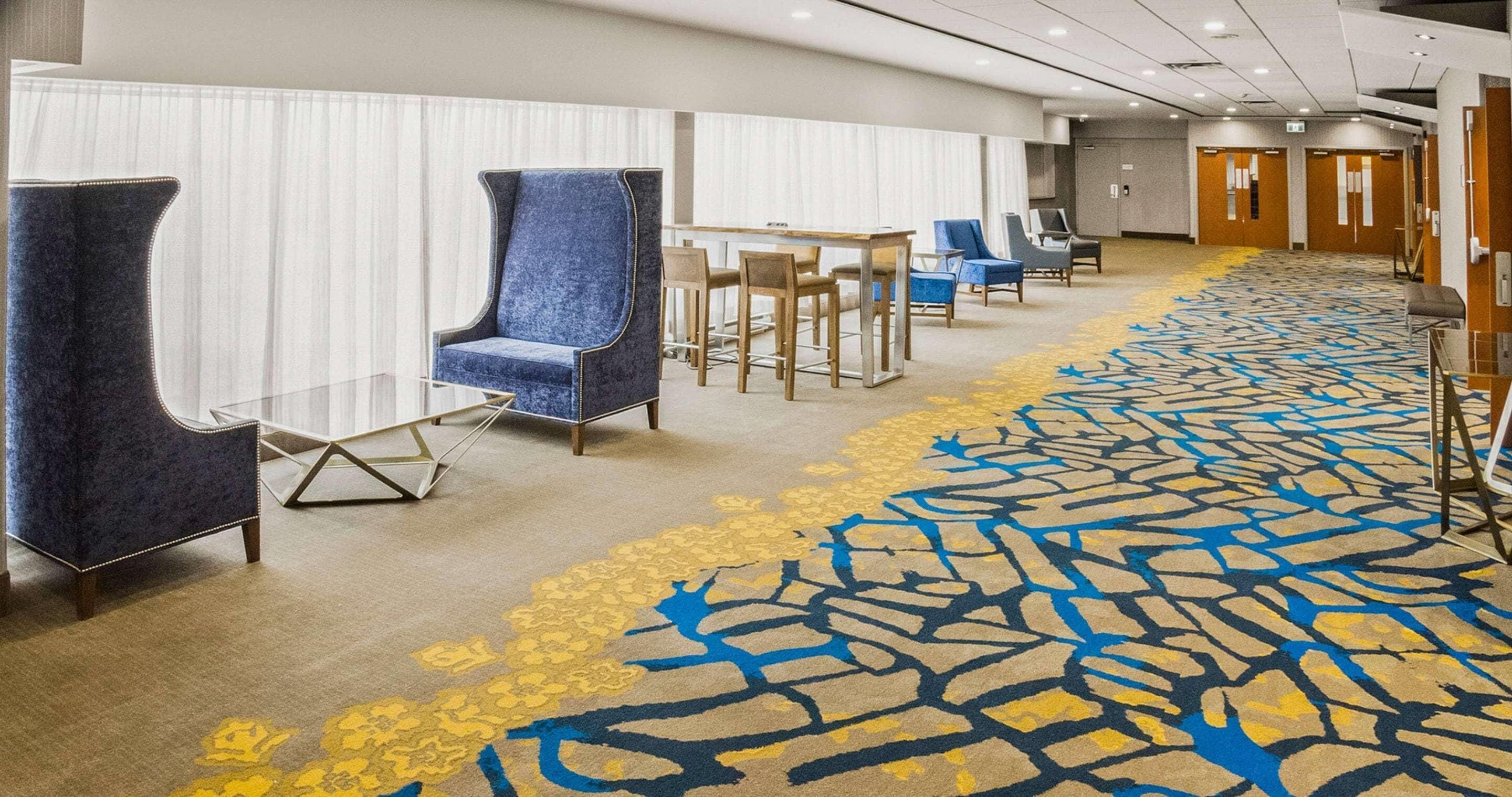 A hotel lobby with a long carpeted corridor, seating area with chairs, and a reception desk. - Radisson Hotel Sudbury (Sudbury)