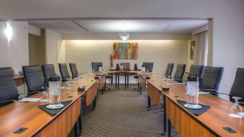 Uma sala de conferências com uma mesa comprida, várias cadeiras e uma mesa central.