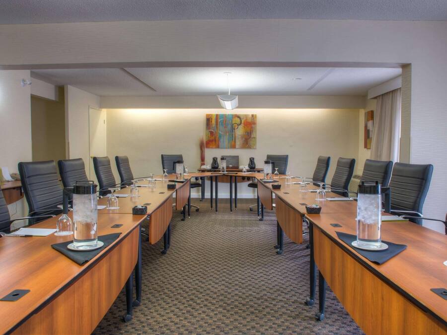 Uma sala de conferências com uma mesa comprida, várias cadeiras e uma mesa central.