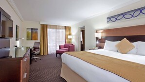 A hotel room with a large bed, a desk, a chair, and a television. - Radisson Hotel Sudbury (Sudbury)