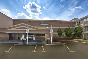A Radisson hotel entrance with a parking lot, a covered walkway, and a landscaped area with trees. - Radisson Hotel Sudbury (Sudbury)