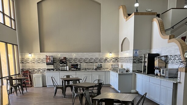 A spacious kitchen with a central island, white cabinetry, and a tiled backsplash. - Ramada by Wyndham Barstow (Barstow)