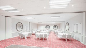 A large conference room with multiple round tables and chairs, white walls, and a red patterned carpet. - Ramada by Wyndham Barstow (Barstow)