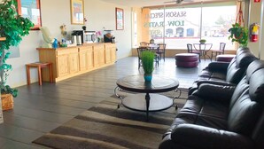 Un vestíbulo amplio con mostrador de recepción, zona de estar y ventanas grandes.