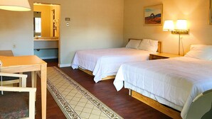 Habitación de hotel con dos camas, un escritorio, una silla, un ventilador de techo y un cuadro en la pared.