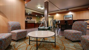 A lobby with patterned armchairs, a round table, and a reception desk. - Best Western Plus Rama Inn & Suites (La Grande)