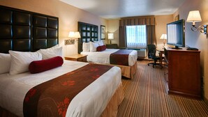 A hotel room with two beds, a desk, a television, and a chair. - Best Western Plus Rama Inn & Suites (La Grande)