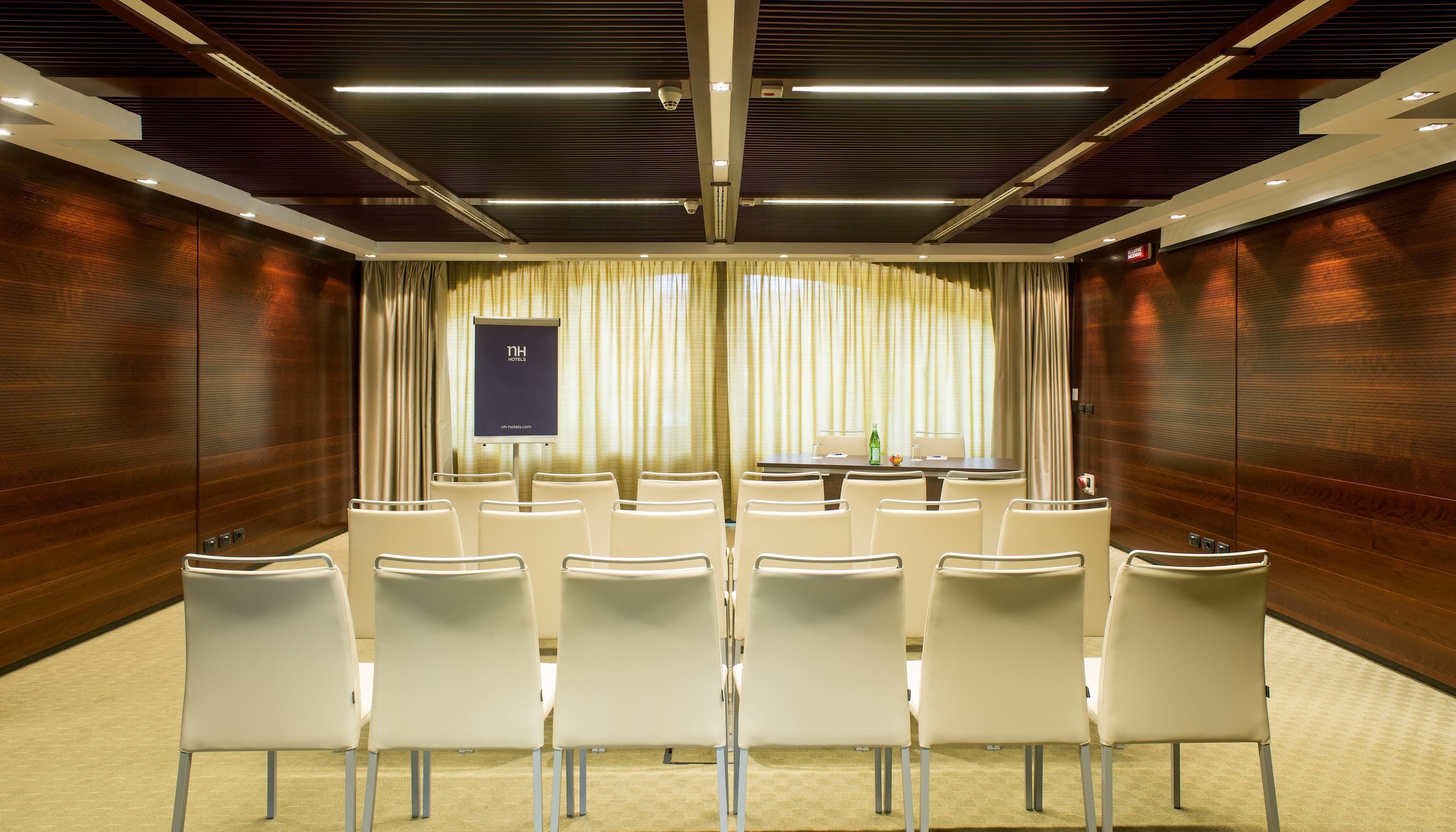 A conference room with a projector screen, white chairs, and a table with a laptop.