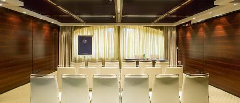A conference room with a projector screen, white chairs, and a table with a laptop.