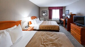 Une chambre d’hôtel avec deux lits, un bureau, une télévision et une chaise.