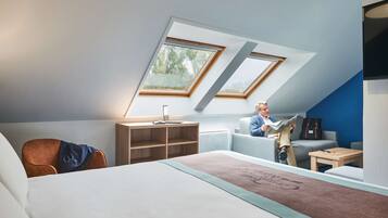 Un dormitorio estilo loft moderno con tragaluces, una cama, un escritorio y una zona de lectura.