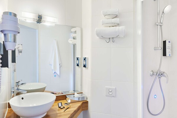 A modern bathroom with a large mirror, two sinks, a shower, and a towel rack. - Kyriad Lille - Mons En Baroeul (Mons-en-Baroeul)