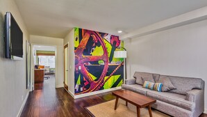 A modern living room with a grey sofa, a wooden coffee table, and a colorful abstract wall mural. - Hotel Indigo Anaheim by IHG (Anaheim)