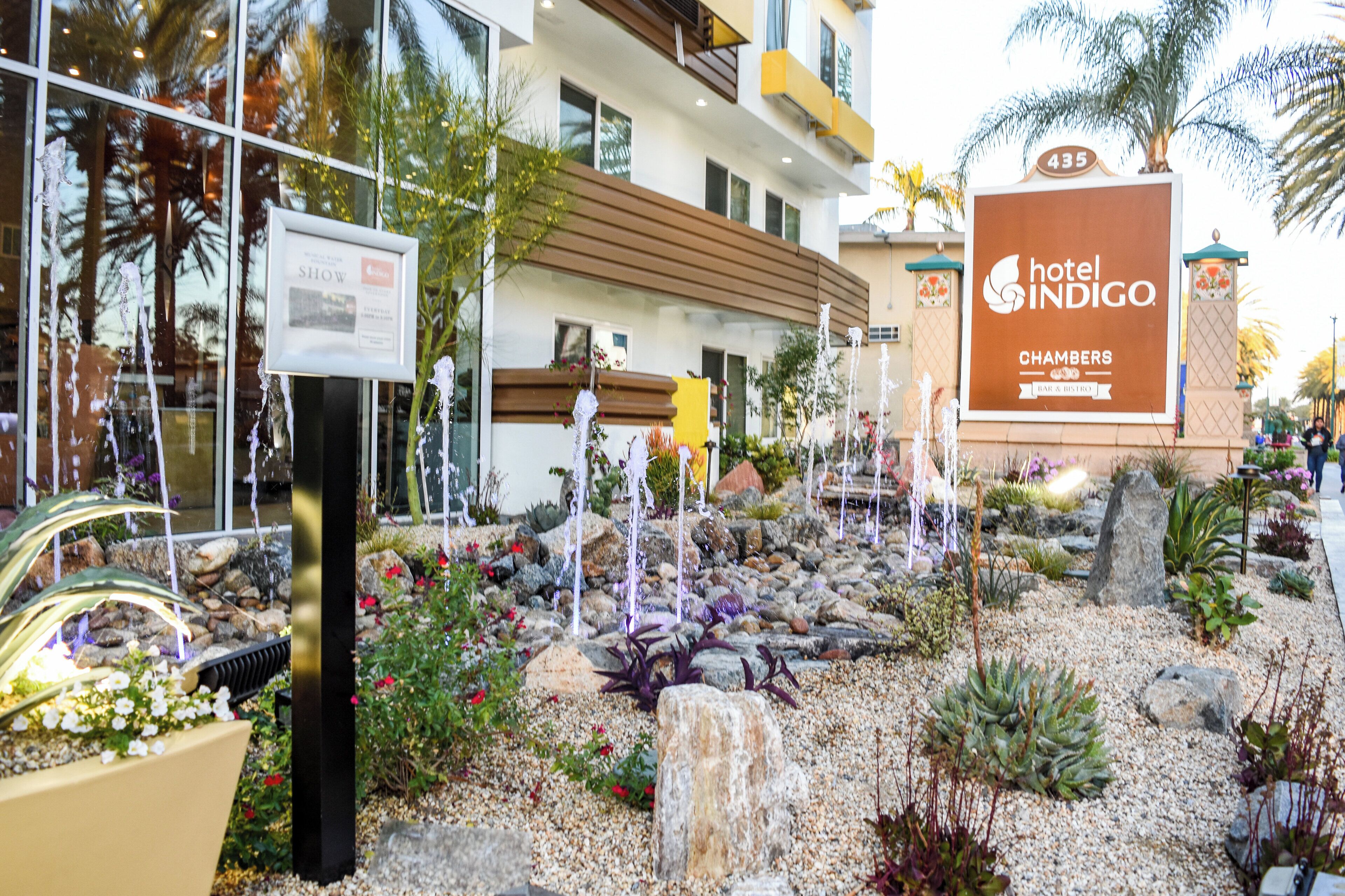 Un hotel con un cartello che indica 'Hotel Indigo Chambers Bar & Bistro' e un giardino curato con una fontana.
