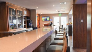 A bar area with a long counter, seating, and a television screen.